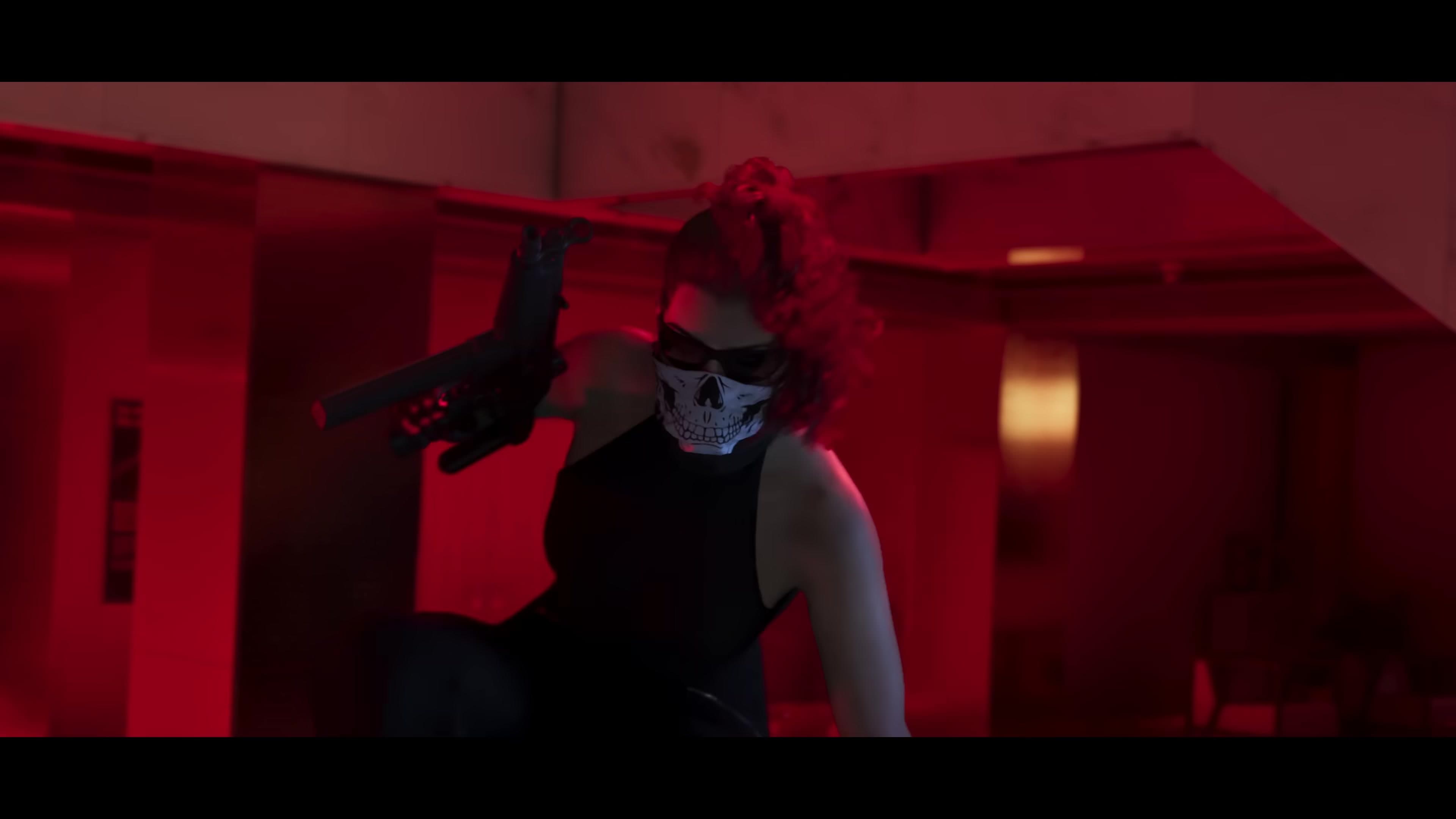 Lucia in a skull mask, aiming a submachine gun (bank robbery)